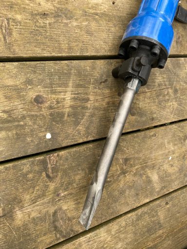 Blauer Abbruchhammer mit einem langen, flachen Meißelaufsatz.